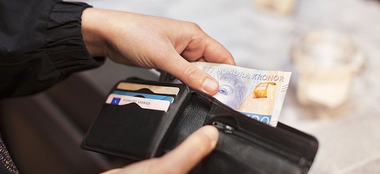 En person tar ut pengar ur en plånbok.