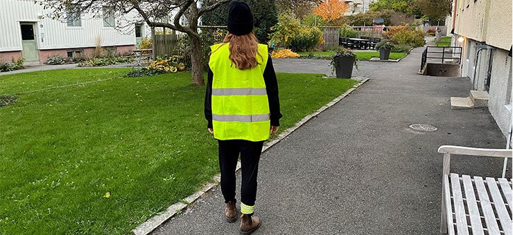 A person wearing a hi-vis vest and reflector bands on their trouser legs.