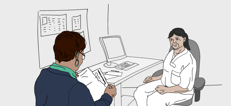 Läkare sitter i samtal med patient på läkarmottagning.