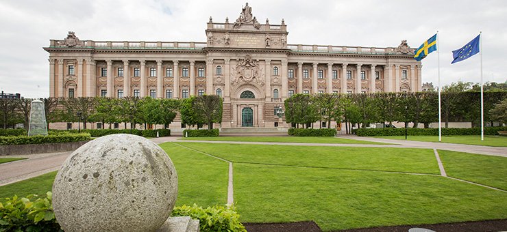 ساختمان شرقی پارلمان با پرچم سوئد و پرچم اتحادیه اروپا که باد آنها را به اهتزاز در آورده است. 