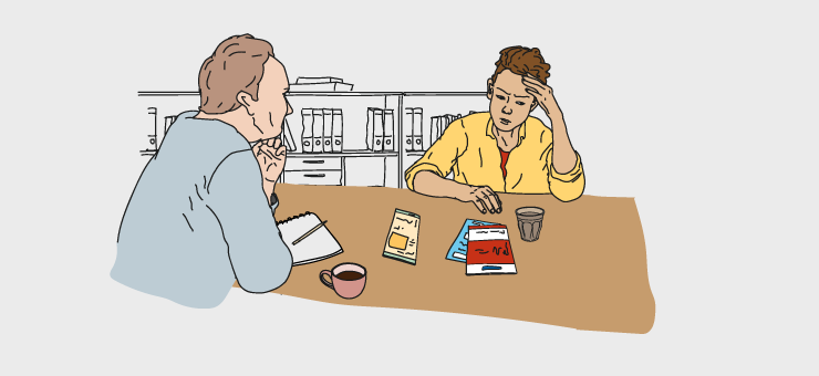 Una persona joven conversa con otra adulta junto a una mesa en una consulta juvenil.